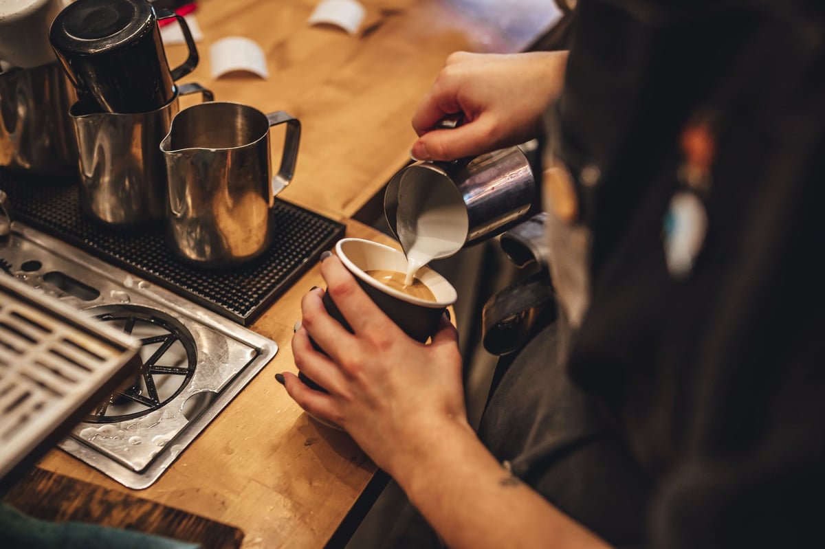 Artisan coffee shop barista making latte art