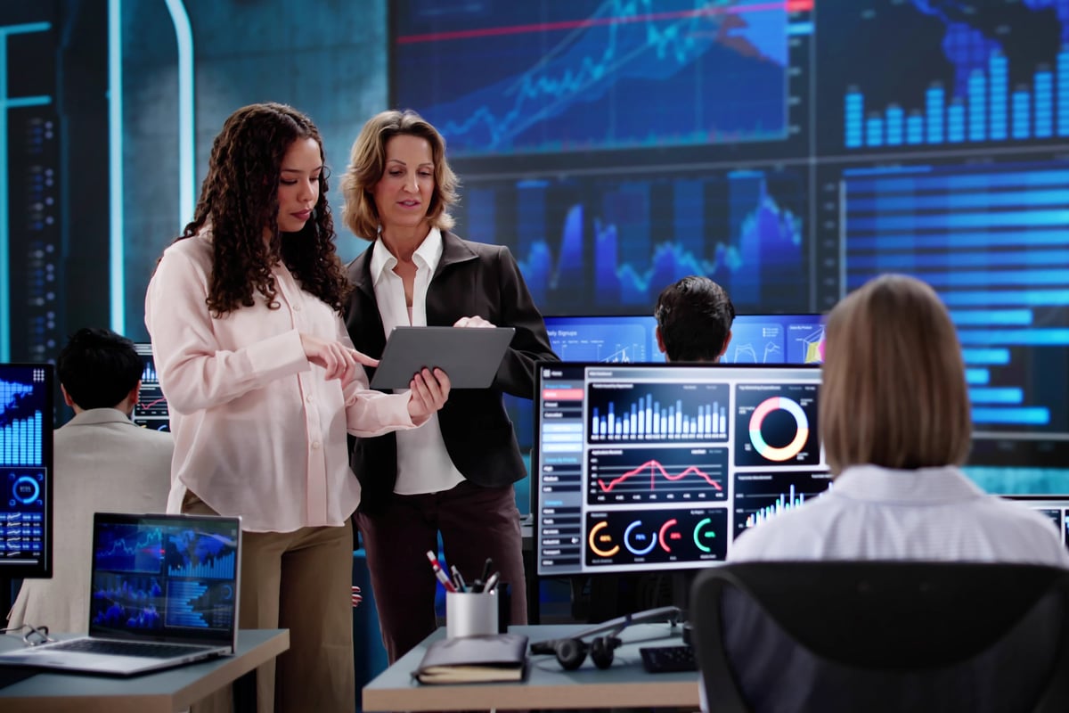 Modern tech startup team working on software development with data dashboards on screens